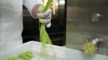 Şef mutfakta fesleğenli yeşil makarna hazırlıyor.