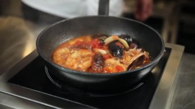 Şef mutfakta deniz mahsullü yeşil makarna hazırlıyor.