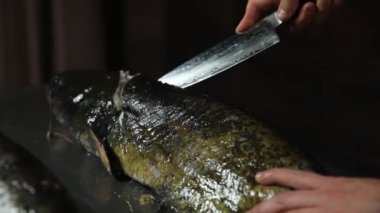 Şef büyük bir yayın balığı kesiyor. 