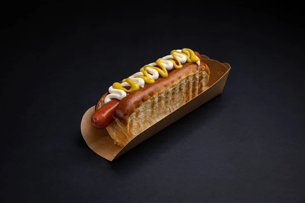 用香肠和酱汁包在纸盘里的热狗 — 图库照片