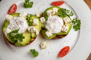 Bir restoranda ahşap bir masada avokadolu sandviç ve haşlanmış yumurta.