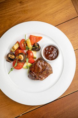 Garnitürlü biftek ve tabakta sos.