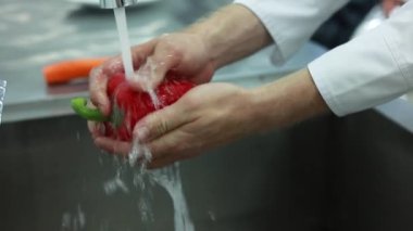 Adam mutfak lavabosunu taze sebzelerle yıkıyor.