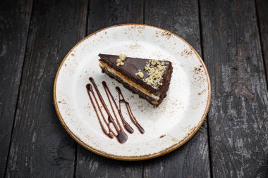 Tahta arka planda kremalı ve fındıklı çikolatalı pasta.