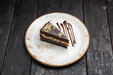 Tahta arka planda kremalı ve fındıklı çikolatalı pasta.