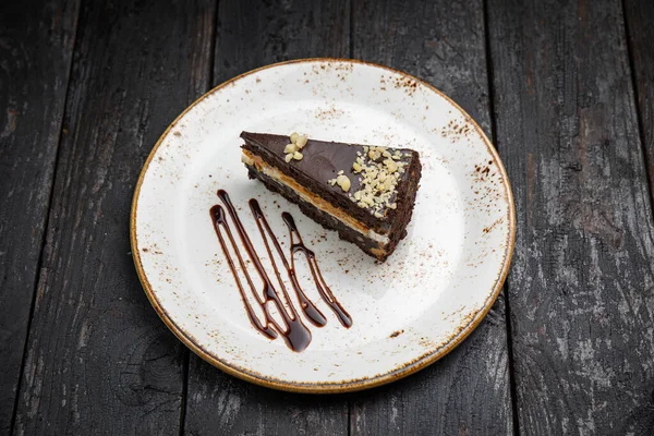 Tahta arka planda kremalı ve fındıklı çikolatalı pasta.