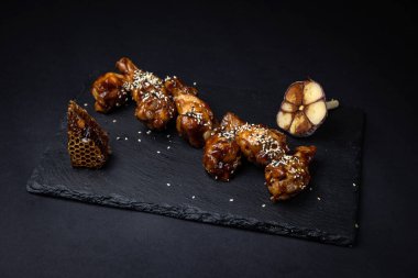 ızgara tavuk kanadı ve susam tohumları ve siyah arka planda baharatlar.