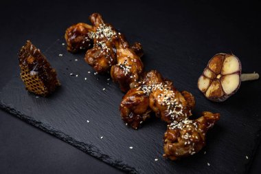 ızgara tavuk kanadı ve susam tohumları ve siyah arka planda baharatlar.