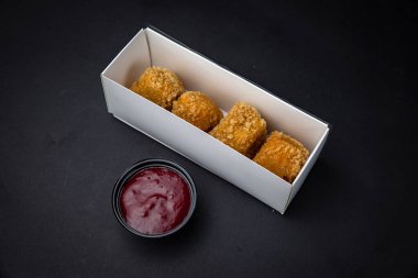 Soslu tavuk nugget ve siyah arka planda ketçap.