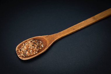 wooden spoon with dried black pepper on a dark background