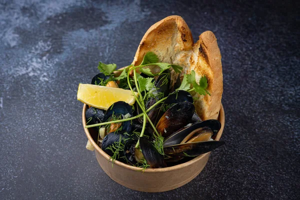 mussels in a cardboard disposable plate with lemon and parsley