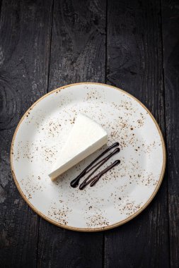 piece of cheesecake with cream and chocolate on a white plate
