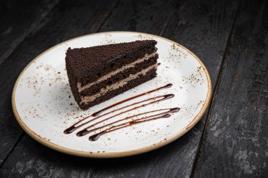 chocolate cake with cream and nuts on a black plate