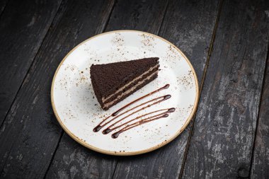 Tahta arka planda kremalı ve fındıklı çikolatalı pasta.