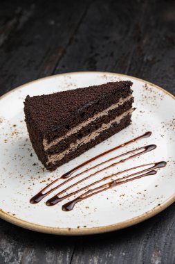 Tahta arka planda kremalı ve fındıklı çikolatalı pasta.