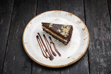 Tahta arka planda kremalı ve fındıklı çikolatalı pasta.