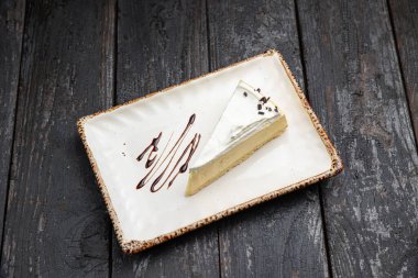 piece of cheesecake with cream and chocolate on a white plate