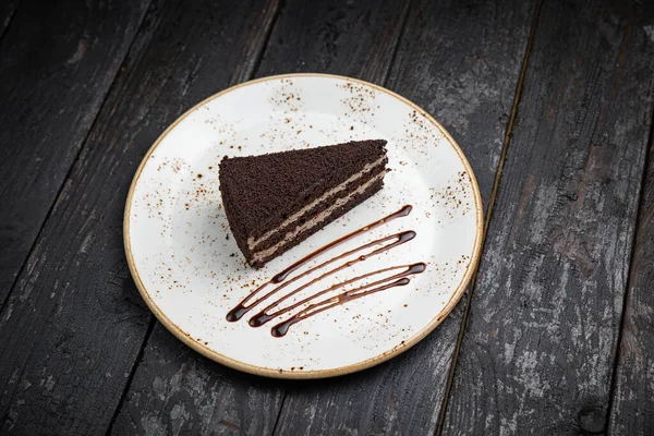 Tahta arka planda kremalı ve fındıklı çikolatalı pasta.