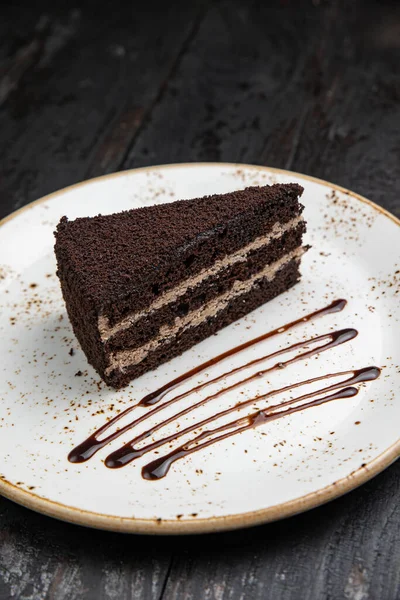 Tahta arka planda kremalı ve fındıklı çikolatalı pasta.