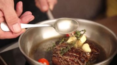 the chef cooks a steak in a frying pan