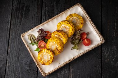 Koyu ahşap bir masada ızgara sebze yemek.