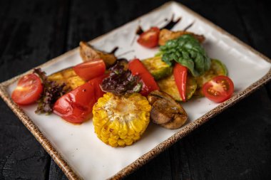 Koyu ahşap bir masada ızgara sebze yemek.