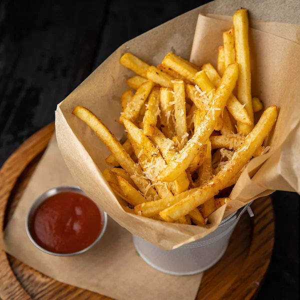 Koyu ahşap bir masada domates soslu patates kızartması.