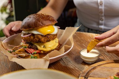 Tavuklu hamburger, domates ve ahşap zemin üzerinde soğan.
