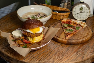 burger with beef, cheese and vegetables on a wooden table