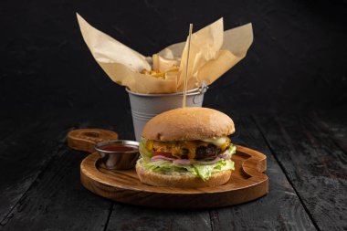 Ahşap arka planda sığır etli, peynirli ve domates soslu hamburger.