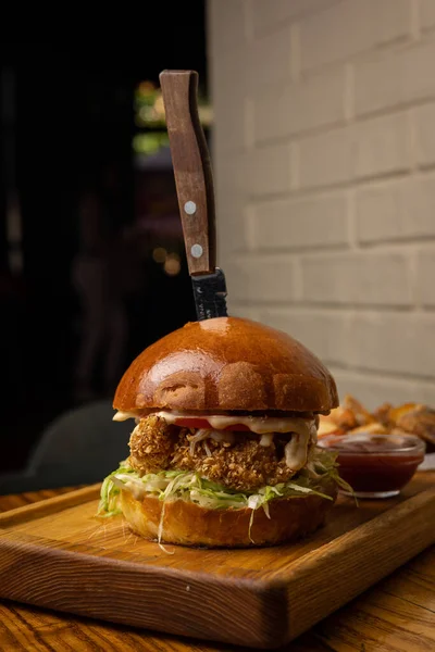 burger with chicken, tomato and onion on wooden background