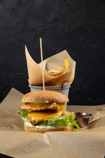 delicious burger with chicken, cheese and lettuce on black background