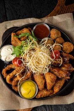 Siyah arka planda bir tavada haşlanmış deniz ürünleri.