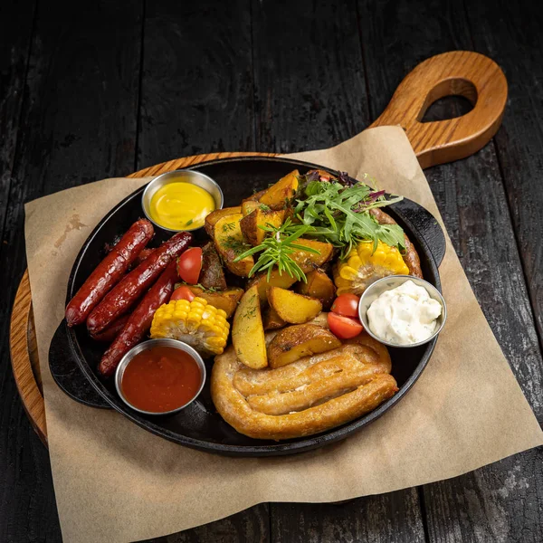 Siyah arka planda tavada ızgara sosis.