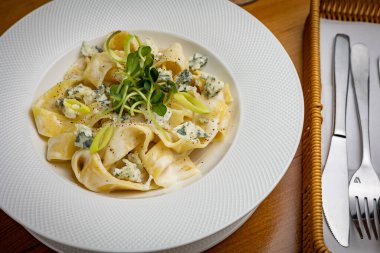 Peynirli makarna, yeşillik, restoranda sos.