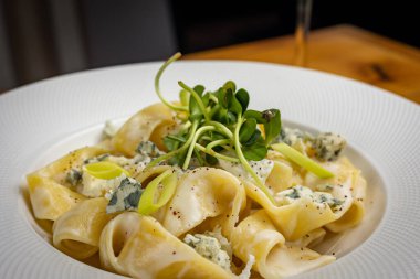 Peynirli makarna, yeşillik, restoranda sos.