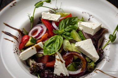 Beyaz arka plandaki tabakta beyaz peynirli ve roka soslu salata.