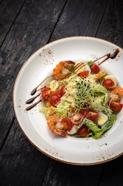 Karides ve yumurta ile kızartılmış deniz ürünleri, siyah tabakta Asya yemeği tarzında.