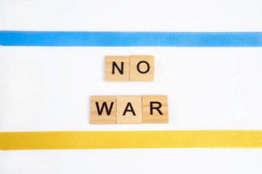 Beyaz arka planda izole edilmiş ahşap karelerden hiçbir savaş çıkarılamaz. Mavi ve sarı kurdeleli Ukrayna bayrağıyla. Barış kavramı, Ukrayna 'da savaş