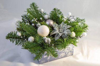 Kozalaklı Noel kompozisyonu ve mavi bir kutuda beyaz toplar..
