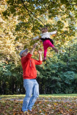 Baba, yeni yürümeye başlayan kızına tekmeyi basıyor. Aile eğlencesi baba ve çocuk parkta oynuyorlar..
