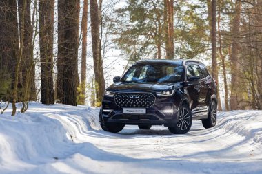 Moskova, Rusya - 18 Mart 2021: Yeni yedi koltuklu minivan Chery Tiggo 8 profesyonel. Çin arabası kışın bir orman yolunda durur.