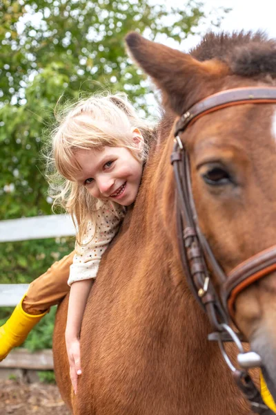 Little girl hugs pony horse and laugh happily — Stock Photo, Image