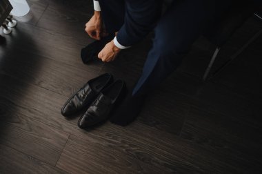 Takım elbiseli bir adam, damat, yakın plan ayakkabılarını giyer, bağcıklarını bağlar.
