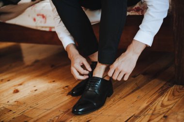 Takım elbiseli bir adam, damat, yakın plan ayakkabılarını giyer, bağcıklarını bağlar.