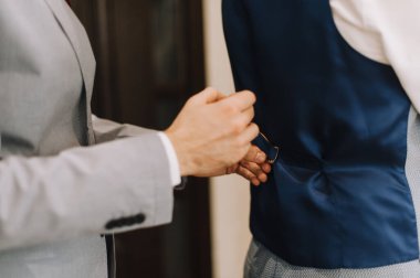 Damadın arkadaşı giyinmeye yardım ediyor.