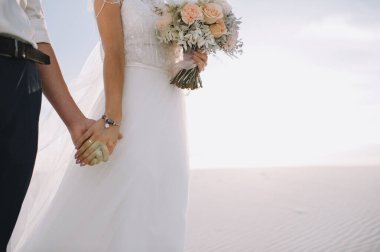 Birbirini seven yeni evliler nazikçe el ele tutuşuyorlar.