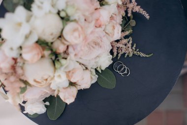 Gelin çiçeğinin arka planında değerli taşlar olan alyanslar.