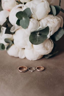 Gelin çiçeğinin arka planında değerli taşlar olan alyanslar.