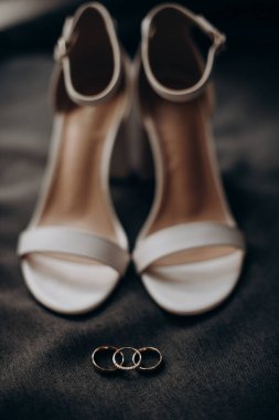 Gelin ayakkabısının arka planında değerli taşlar olan alyanslar.